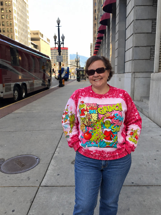 Woman wearing the Mean One Green Guy Bleached Christmas Sweatshirt with jeans on a city sidewalk